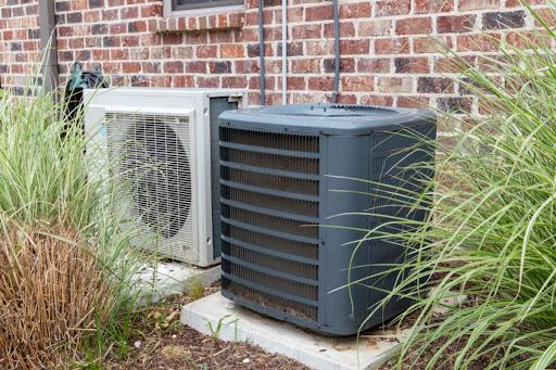 A central air conditioning unit installed next to a heat pump unit outside of a residential building.